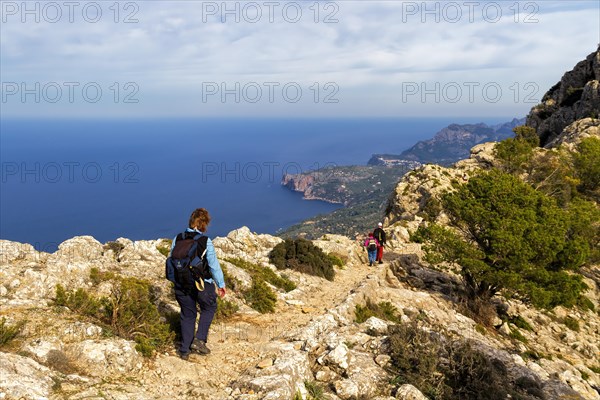 Hikers on a mountain path with panoramic views of the sea and coastline, Hiking tour in Taix massiv, Mallorca