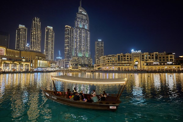 Dubai, United Arab Emirates, AsiaTourists ride in a boat in front of the skyscraper backdrop at Lake Burj Khalifa, Asia