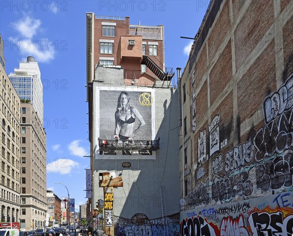 Painter on hanging scaffolding creating mural, advertisement with woman in bikini, graffiti on house wall, SoHo neighbourhood, Manhattan, New York City, New York, USA, North America