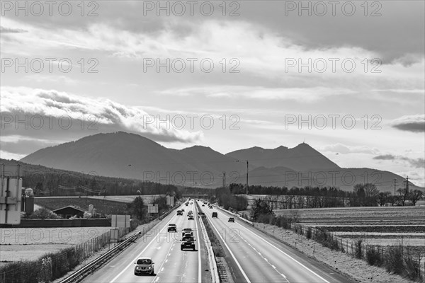 Busy motorway in front of a mountain backdrop in black and white with cloudy sky, Neunkirchen, Lower Austria, Austria, Europe