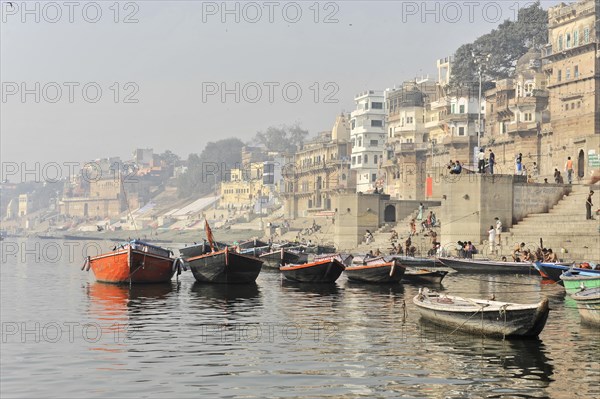 Quiet boats on a misty river against a backdrop of old buildings on the city bank, Varanasi, Uttar Pradesh, India, Asia