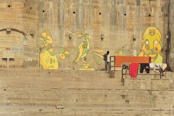 Fresh murals on the ghats of a river, people going about their daily routines, Varanasi, Uttar Pradesh, India, Asia
