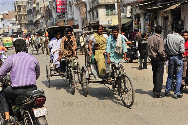 People travelling in cycle rickshaws on a busy street with shops, Varanasi, Uttar Pradesh, India, Asia