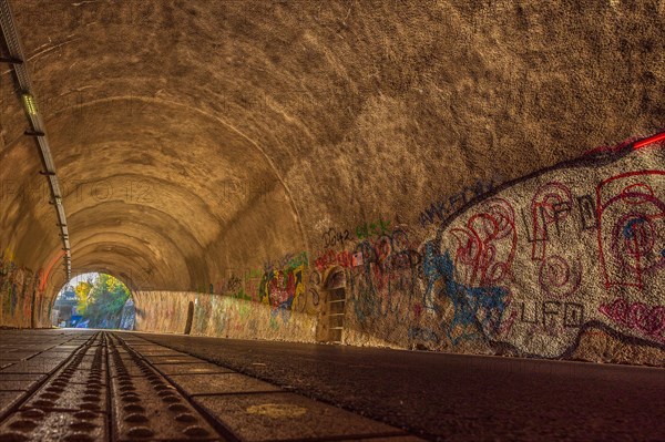 Cycle path through a tunnel with colourful graffiti on the walls and tracks on the floor, Nordbahntrasse, Elberfeld, Wuppertal, Bergisches Land, North Rhine-Westphalia