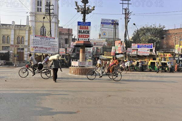 Busy road junction with cyclists and numerous signboards under a clear sky, Varanasi, Uttar Pradesh, India, Asia