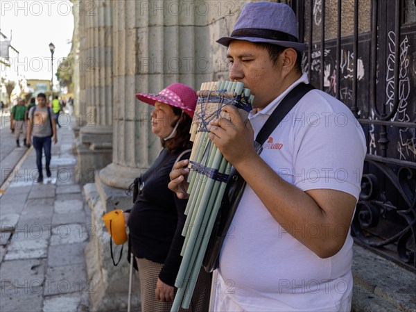 Oaxaca, Mexico, A man plays the pan pipes, while a blind woman collects tips. They are on the Alcala, a pedestrian-only street, Central America