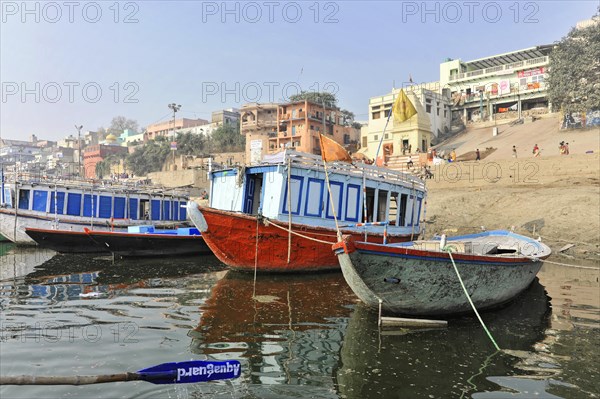 Boats on calm water with city skyline and clear sky, Varanasi, Uttar Pradesh, India, Asia