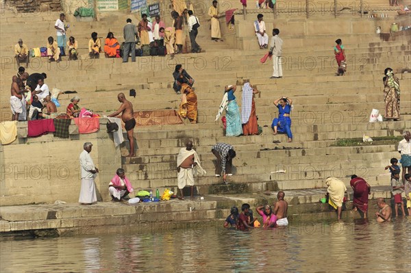 An everyday scenario of people bathing and interacting on a riverbank, Varanasi, Uttar Pradesh, India, Asia
