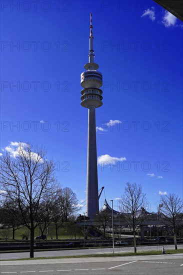A tall television tower rises into the blue sky with trees in the foreground, BMW WELT, Munich, Germany, Europe