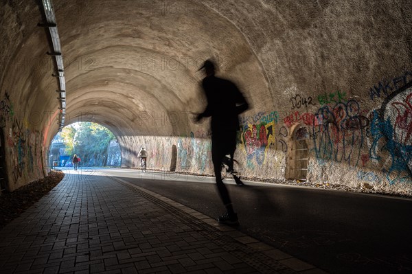 A jogger moves through a tunnel with graffiti and dynamic shadows, Nordbahntrasse, Elberfeld, Wuppertal, Bergisches Land, North Rhine-Westphalia