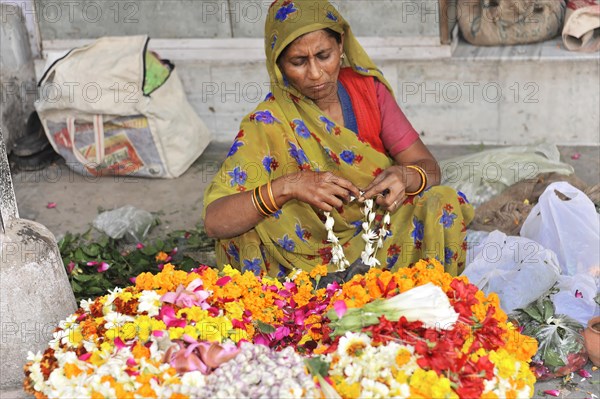 Woman in traditional dress creating handicrafts with flowers at a market, Varanasi, Uttar Pradesh, India, Asia