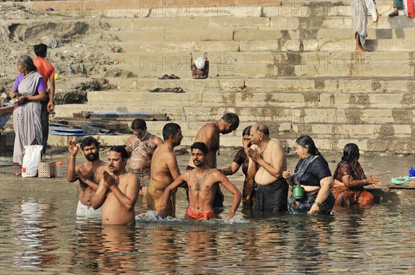 People performing ritual ablutions in the river under the warming morning sun, Varanasi, Uttar Pradesh, India, Asia