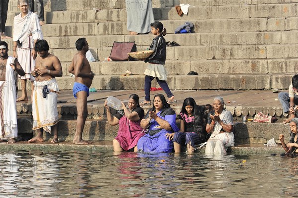 Group of people of different ages in a river during ritual bathing with traditional clothing, Varanasi, Uttar Pradesh, India, Asia