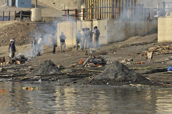 People being cremated near a river, smoke rising and ashes lying on the ground, Varanasi, Uttar Pradesh, India, Asia