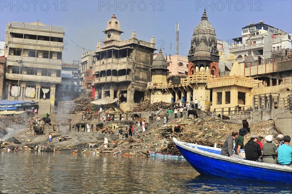 Smoke rises from a traditional funeral fire at the ghats of a river, Varanasi, Uttar Pradesh, India, Asia