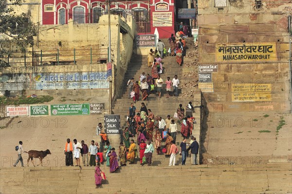 A group of people in traditional dress gather on a riverbank with yoga signs, Varanasi, Uttar Pradesh, India, Asia