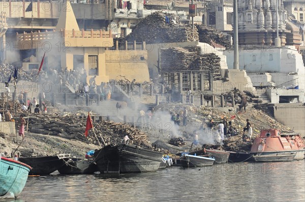 Smoke rises from a traditional funeral fire at the ghats of a river, Varanasi, Uttar Pradesh, India, Asia