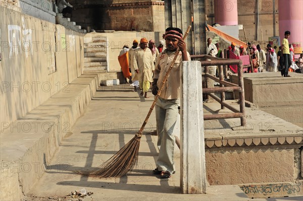 A cleaner sweeps the floor at the ghats of Varanasi in uniform, Varanasi, Uttar Pradesh, India, Asia