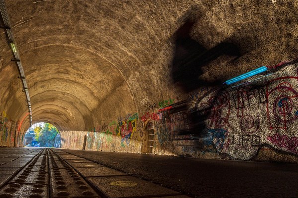 Blurred cyclist in a tunnel whose walls are covered with colourful graffiti, Nordbahntrasse, Elberfeld, Wuppertal, Bergisches Land, North Rhine-Westphalia
