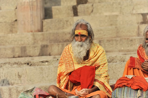 Man in traditional dress meditating on steps in peaceful surroundings, Varanasi, Uttar Pradesh, India, Asia