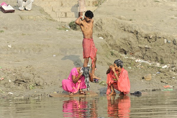 People on the banks of a river during daily washing routines in traditional clothing, Varanasi, Uttar Pradesh, India, Asia