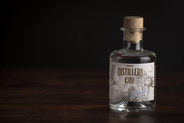 Bottle of gin on a dark wooden table with soft lighting