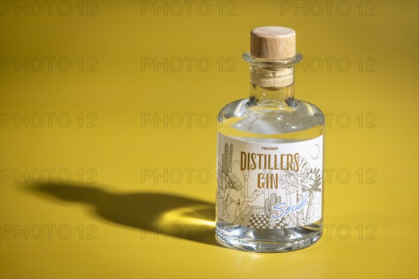 Bottle of gin on a yellow background with interesting shadows