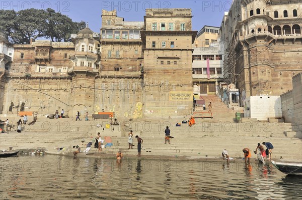View of a busy stretch of river with urban ghats and historic buildings in the background, Varanasi, Uttar Pradesh, India, Asia