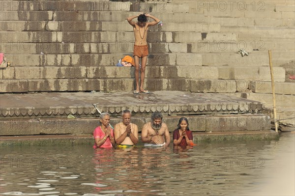 A man and woman in traditional dresses in the shallow water of a river during a ceremony, Varanasi, Uttar Pradesh, India, Asia