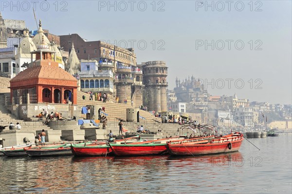 Boats dock at the ghats of a river, with classical Indian architecture in the background, Varanasi, Uttar Pradesh, India, Asia