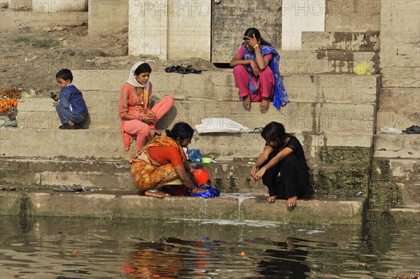 Three woman in traditional dress sitting at the ghats and chatting, Varanasi, Uttar Pradesh, India, Asia