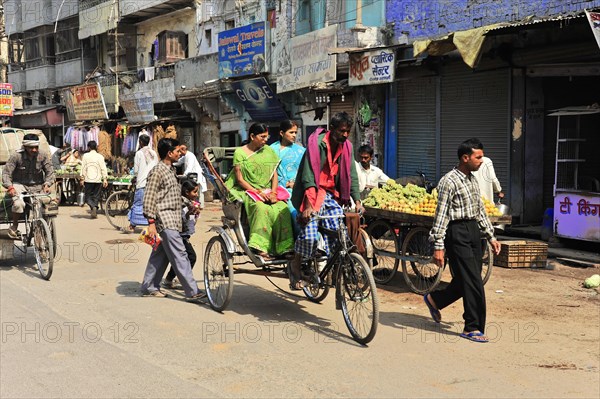 Busy urban scene with rickshaws and pedestrians next to street shops, Varanasi, Uttar Pradesh, India, Asia
