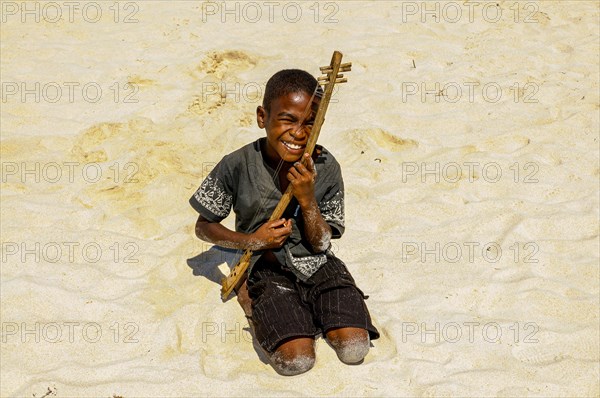 Boy playing on a hand made guitar, Nosy Iranja near Nosy Be, Madagascar, Africa