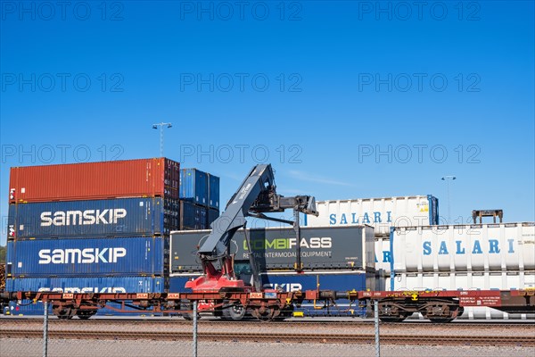 Loading of containers on railway wagons with a lifting crane at a railway depot