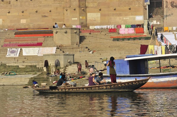 Travellers on a small boat enjoying the river scenery near a clothesline, Varanasi, Uttar Pradesh, India, Asia