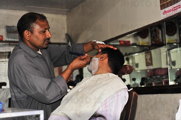 Hairdresser giving a customer a traditional shave in a hairdressing salon, Varanasi, Uttar Pradesh, India, Asia