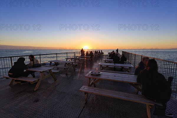 Tourists enjoying sunset on pleasure pier, Royal Pier, Cardigan Bay, Aberystwyth, Ceredigion, Wales, United Kingdom, Europe