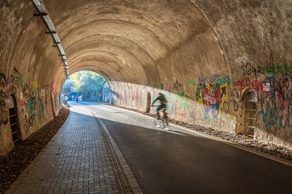 A person on a bicycle rides through a tunnel decorated with graffiti, Nordbahntrasse, Elberfeld, Wuppertal, Bergisches Land, North Rhine-Westphalia