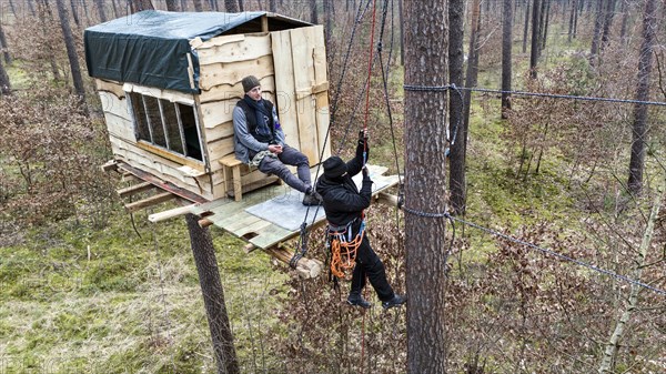 A climate activist pulls herself up a rope to a tree house in the Gruenheide forest. The activist group Stop Tesla has built tree houses in the forest to protest against the planned expansion of the Tesla plant, 04/03/2024