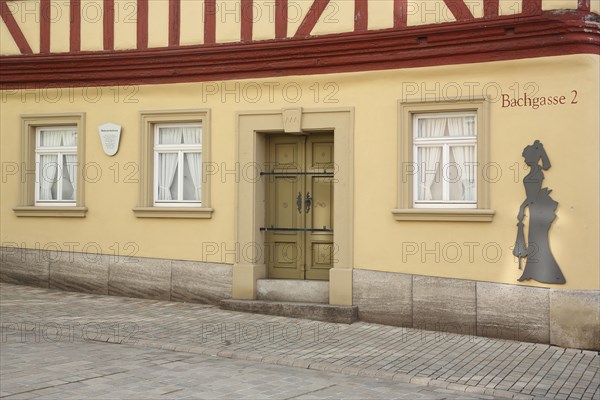 Historic painter's corner house built in 1774 and museum, female figure, lady, silhouette, alleyway name, front door, window, house number, 2, yellow half-timbered house, yellow, Bachgasse, Marktbreit, Lower Franconia, Franconia, Bavaria, Germany, Europe