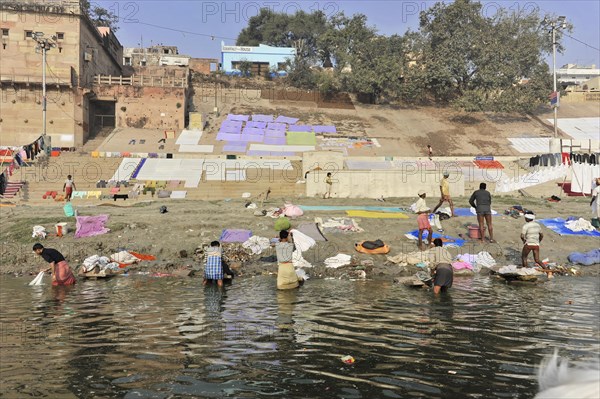 People washing clothes in a river against a colourful backdrop, Varanasi, Uttar Pradesh, India, Asia