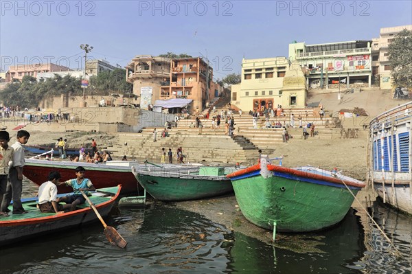 People and boats on the lively riverbank with visible city steps, Varanasi, Uttar Pradesh, India, Asia