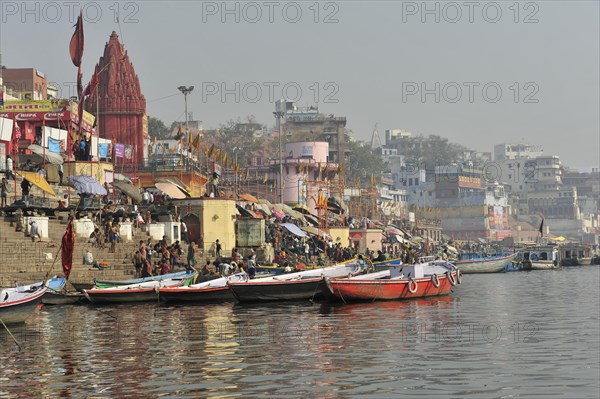 View of boat-filled ghats and a riverside temple, sign of religious activity, Varanasi, Uttar Pradesh, India, Asia