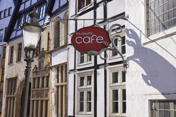 Historic facades, lantern and sign for the museum cafe in backlighting in the Schnurrviertel in the historic centre of Minden, Muehlenkreis Minden-Luebbecke, North Rhine-Westphalia, Germany, Europe