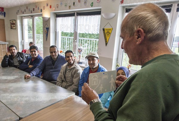 Syrian refugees learn traffic rules during an integration course. An employee of the Oberspreewald-Lausitz district and traffic watch organisation shows and explains traffic signs and rules to the refugees in the rooms of the Grossraeschen sports club, 05/10/2016