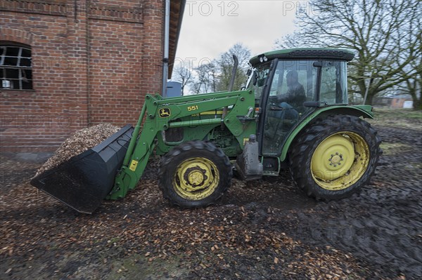 Tractor loading woodchippings on a farm, Othenstorf, Mecklenburg-Vorpommern, Germany, Europe