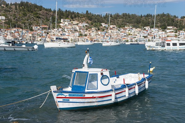A moored boat in a quiet harbour with a view of sailing boats and white coastal houses, view from Galatas, Argolis, to Poros, Poros Island, Saronic Islands, Peloponnese, Greece, Europe
