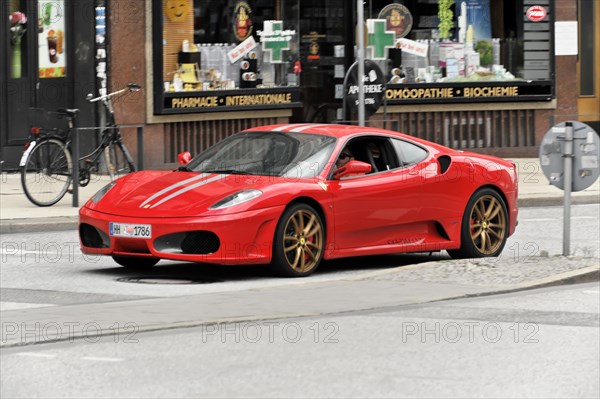 A red Ferrari sports car driving on a city street, Hamburg, Hanseatic City of Hamburg, Germany, Europe