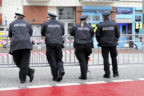 Four police officers in uniform watching a cordon on a street, Hamburg, Hanseatic City of Hamburg, Germany, Europe