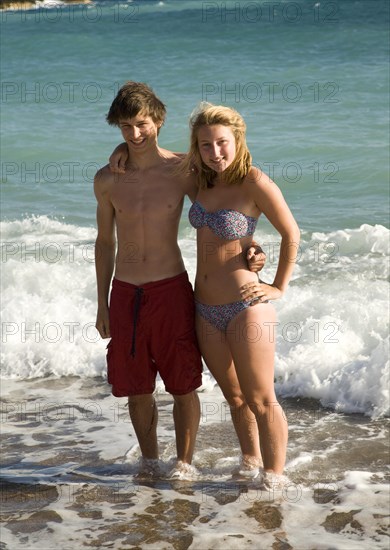 Model released smiling brother and sister twins stand in the sea together, Rhodes, Greece, Europe